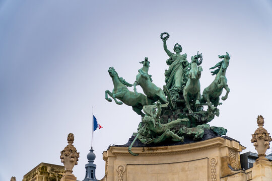 D&eacute;tail de la statue monumentale en bronze du quadrige sur le toit du Grand Palais avec le drapeau fran&ccedil;ais, Paris, France.