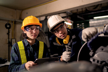 Fototapeta premium Two Industrial Technicians Collaborating to Inspect Heavy Machinery in Factory Workshop Representing Teamwork, Engineering Maintenance, Equipment Inspection and Workplace Safety