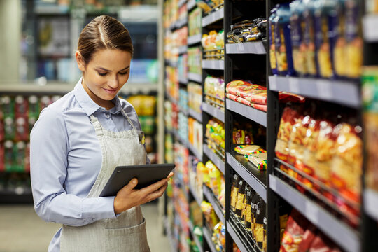 Aisle, inventory and woman with tablet in supermarket for storage inspection or stock management. Female person, packer or store clerk with technology for product checklist, shop or essential service