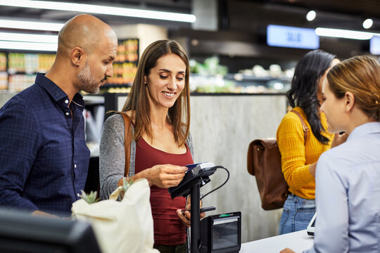 Credit card, grocery and payment with couple in supermarket for shopping, retail and sales. Digital transaction, discount and food coupon with happy people in store for customer and promotion code