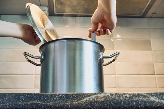 Person stirring broth in steaming pot on kitchen countertop