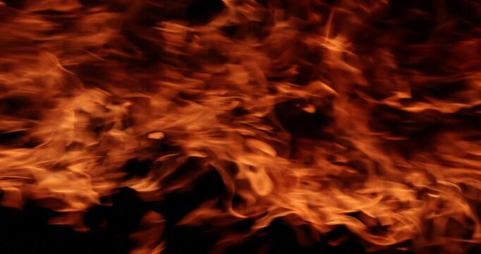 Enormous and vigorous flames burn with remarkable intensity. Raging fire casts warm and brilliant radiance across nighttime environment