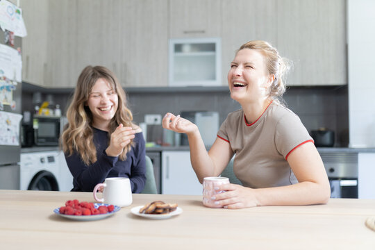 Mother and daughter laughing enjoying breakfast together