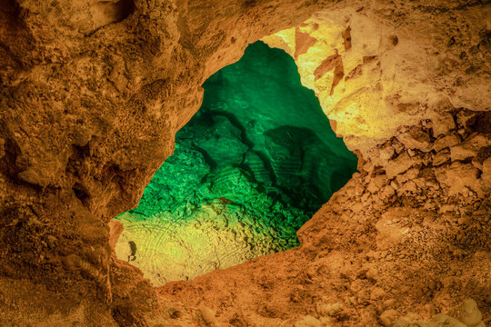 San Vittore, Marche, Italy - 23 April 2023: View of the vibrant green water pool inside the Frasassi Caves, featuring rugged limestone rock formations and natural subterranean lighting.