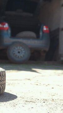 Car wheels rolling on the ground in front of car garage