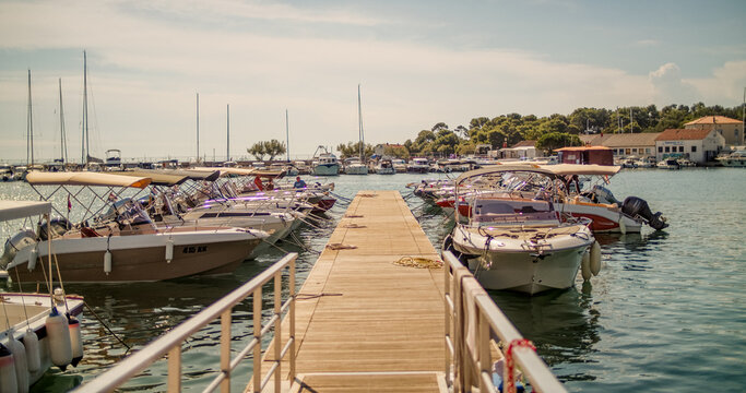 Krk, Primorje-Gorski Kotar, Croatia - 19 September 2026: View of motorboats moored along a wooden pier in the harbor with calm water and coastal buildings in the background.