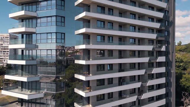 Modern apartment building facade with glass reflections and white balconies