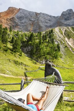 Female hiker resting in hammock at mountain hut on Tre Cime trail in Dolomites enjoying alpine scenery wellness adventure and hiking break