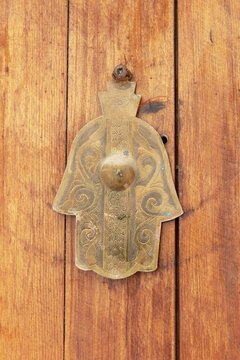 Ornamental brass handle in the shape of a hand on wooden door