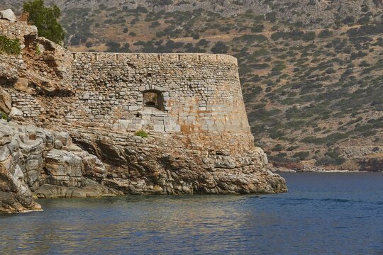 Historic fortress wall on a rocky coastline, with clear blue sky and calm waters, Venetian Sea Fortress, Leper Island, Spinalonga, Elounda Bay, Mirabello Bay, East Crete, Crete, Greek Islands, Greece