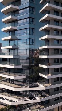 Modern apartment building facade with glass reflections and white balconies