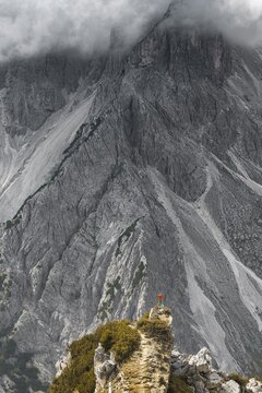 Mountaineer, woman standing on a ridge and looking into a cirque, clouds, in the back rock faces of Cimon di Croda Liscia, Auronzo di Cadore, Belluno, Italy