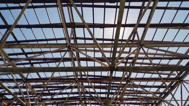 Metal roof frame structure of abandoned building against sunny sky