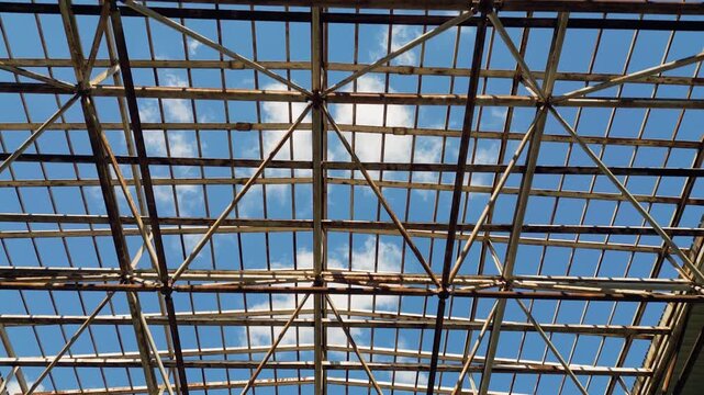 Metal roof frame structure of abandoned building against sunny sky