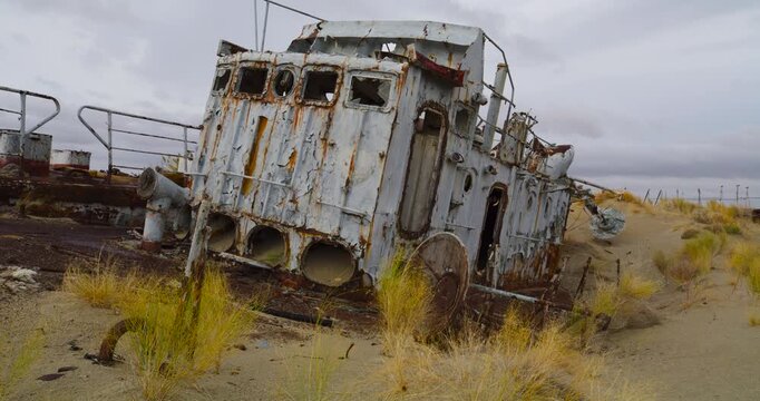 An abandoned rusty boat sits decaying in the Aral Sea desert landscape.