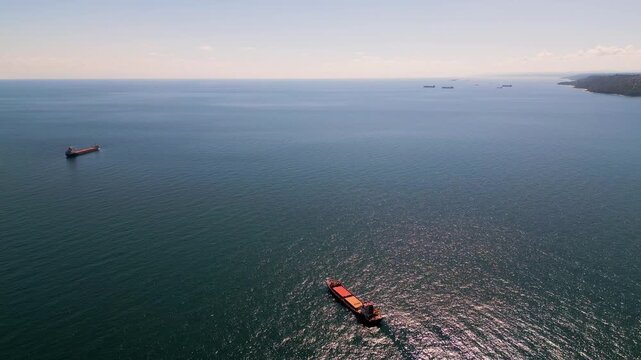 Aerial view of cargo ships and tankers anchored in open calm blue sea waters