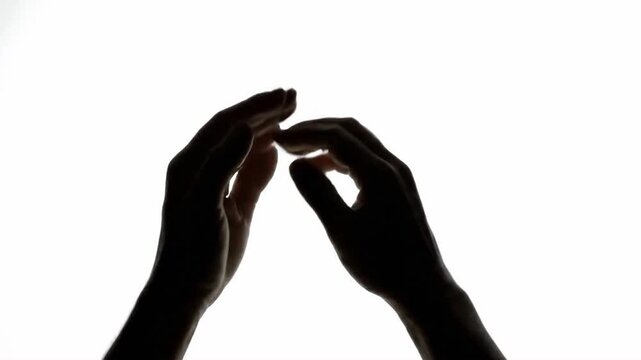 Human hands outlined against a bright background in a vertical display