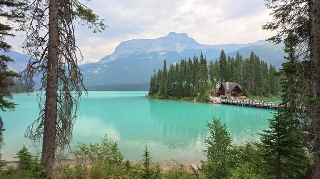 Emerald Lake's turquoise water reflecting surrounding mountains, with charming lodge and canoes inviting summer recreation and peaceful nature escape in Yoho National Park, British Columbia, Canada