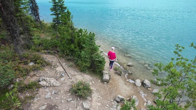 top view of Woman standing by the vibrant turquoise water of Emerald Lake in Yoho National Park, British Columbia, enjoying the peaceful summer scenery and clear mountain lake view in Canada