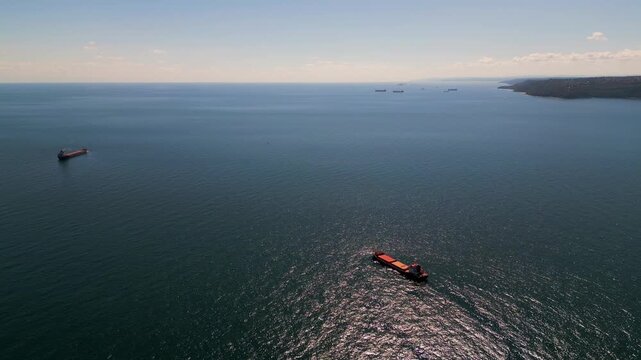 Aerial view of cargo ships and tankers anchored in open calm blue sea waters