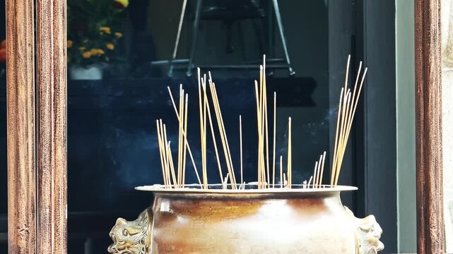 Close up of many incense sticks burning at the entrance of a Buddhist temple