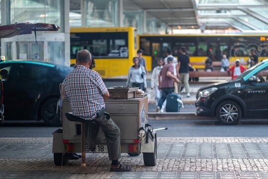 Lisboa, Portugal - 19 September 2026: View of a man sitting at a mobile food cart at the Gare do Oriente transport hub with buses and commuters in the background.