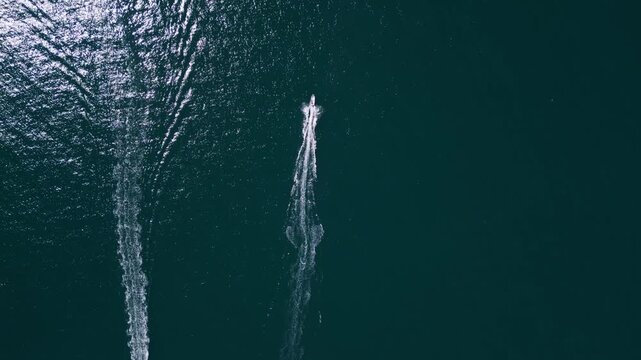 Aerial top down view of two motorboats speeding across deep blue ocean water