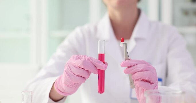 Female assistant hands hold capsule and test tube with pink liquid in lab slow motion. Female pharmacist works on drugs in healthcare laboratory