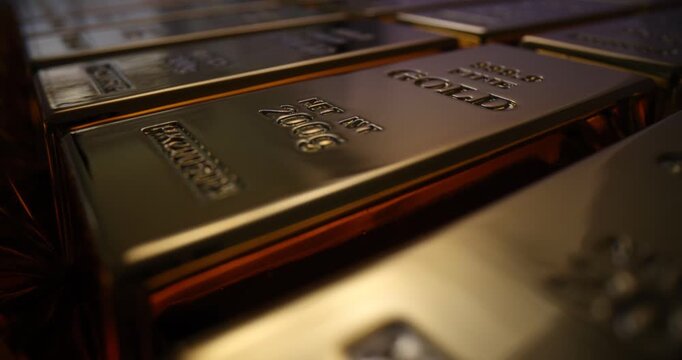 Glossy gold ingots with stamped weight and fineness marks on surface. Rows of expensive precious metal bars arranged symmetrically at soft light