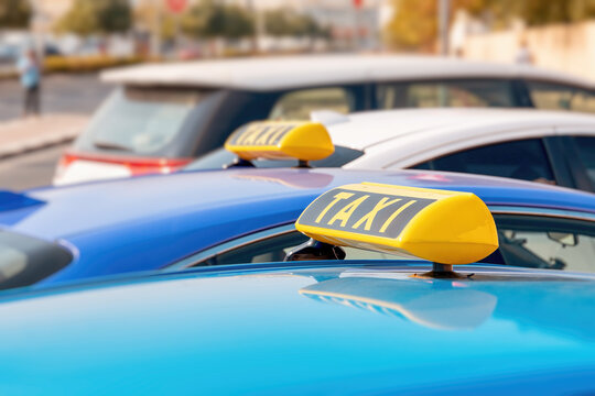 taxi cabs with yellow roof signs waiting for passengers in an urban street during the day