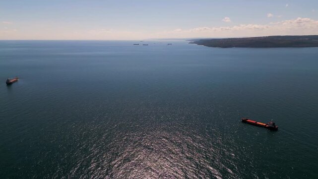 Aerial view of cargo ships and tankers anchored in open calm blue sea waters