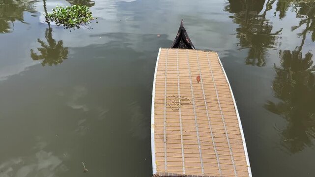 Boatman rowing a traditional wooden boat through the tranquil backwaters of Kerala, India