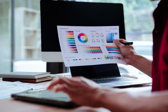 Creative designer reviewing color palettes, architectural concepts, and visual plans on a computer in a modern workspace.