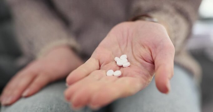 Female hand holds several white pills during medication use. Patient opens palm displaying tablets preparing prescribed medicine for treatment