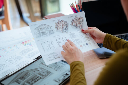 Creative designer reviewing color palettes, architectural concepts, and visual plans on a computer in a modern workspace.