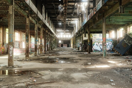 Leipzig, Germany - 15 September 2026: View of an abandoned industrial factory interior with graffiti-covered walls, rusted metal pillars, and debris on the concrete floor.