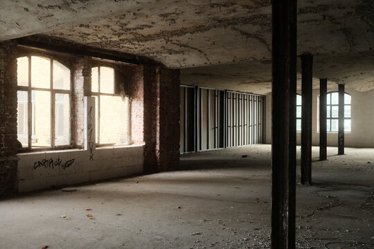 Leipzig, Germany - 15 September 2026: View of an abandoned industrial interior with exposed brick walls, large arched windows, and metal support columns in a building under renovation.