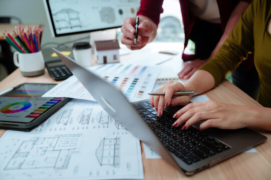 Creative designer reviewing color palettes, architectural concepts, and visual plans on a computer in a modern workspace.