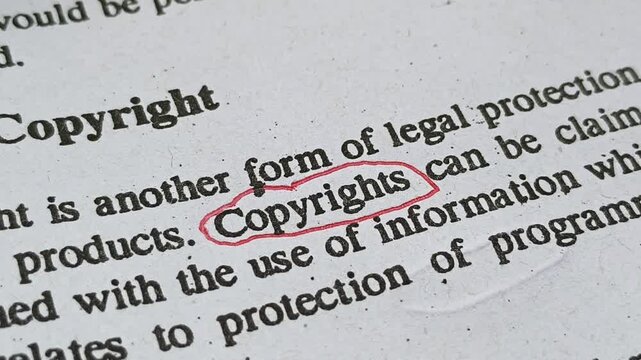 Hand with pen mark circle around to emphasize or highlight copyrights word on legal business contract document page. Concept of attorney review intellectual property protection compliance agreement.