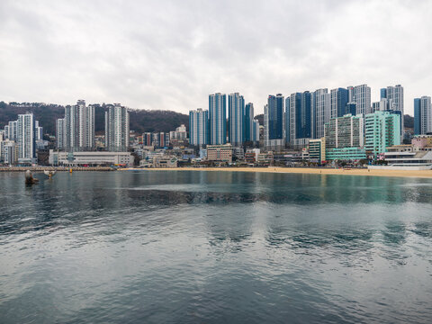 Busan, South Korea - 07 February 2026: View of the modern skyline of high-rise apartment buildings along the sandy Songdo Beach under a cloudy sky.