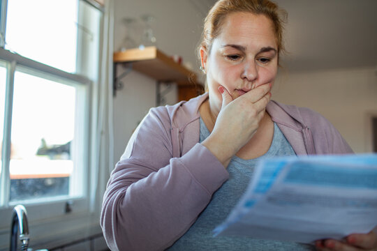 Worried woman reading a bill at home