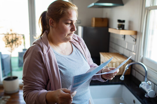 Worried woman reviewing household bills in the kitchen