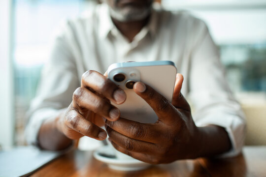 Close-up of man texting on smartphone at cafe