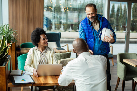 Contractor greeting clients with handshake in cafe