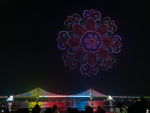 Busan, South Korea - 14 February 2026: View of a drone light show forming a colorful floral pattern above the illuminated Gwangan Bridge at night.