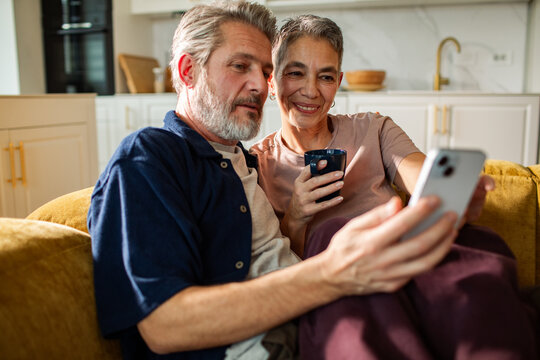 Older couple on sofa looking at smartphone at home