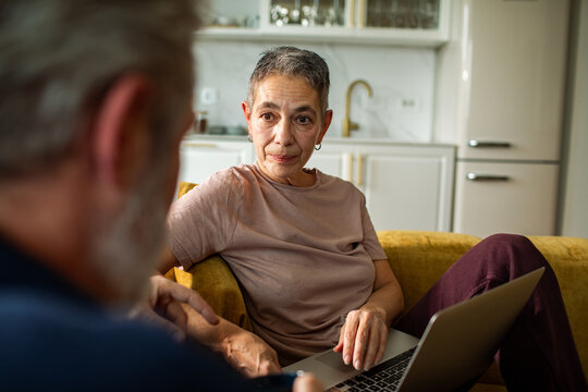 Senior woman listening to partner while using laptop at home