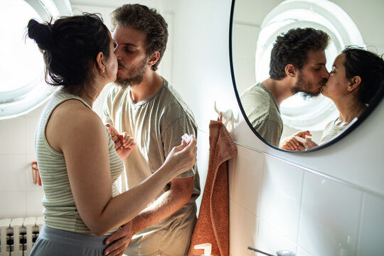 Couple share a kiss in a home bathroom mirror