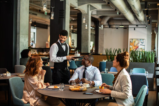 Waiter serving coffee to business colleagues in restaurant