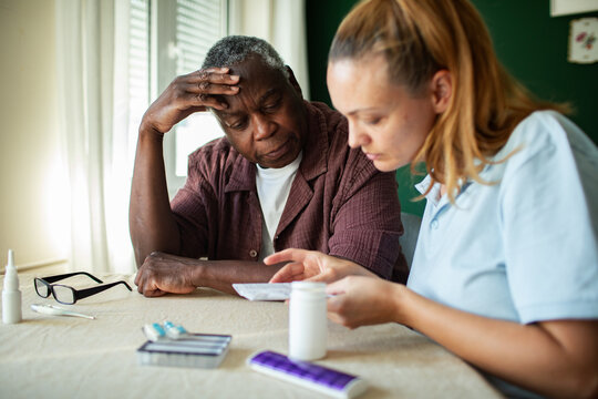 Caregiver explaining medication instructions to senior man at home